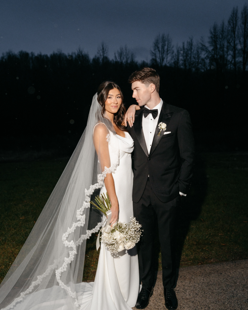 Bride and groom in modern black tie attire posing outdoors at The Lumen House in Cleveland North Carolina at night with dramatic lighting