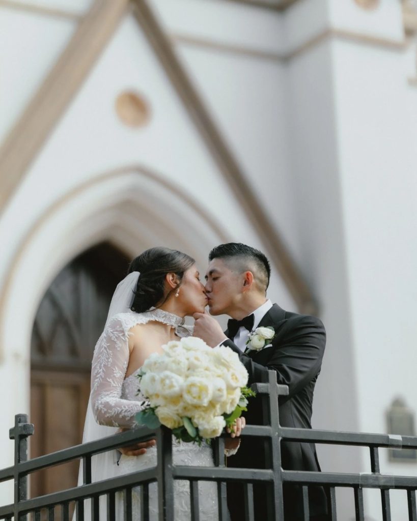 Bride and groom kissing outside Savannah church after ceremony with white rose bouquet, planned by Enchanted Alice Events.