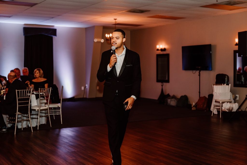 DJ Tycoon with microphone working the crowd at a wedding reception.