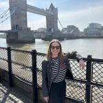 girl posing in front of london bridge from trip planned by travel agent