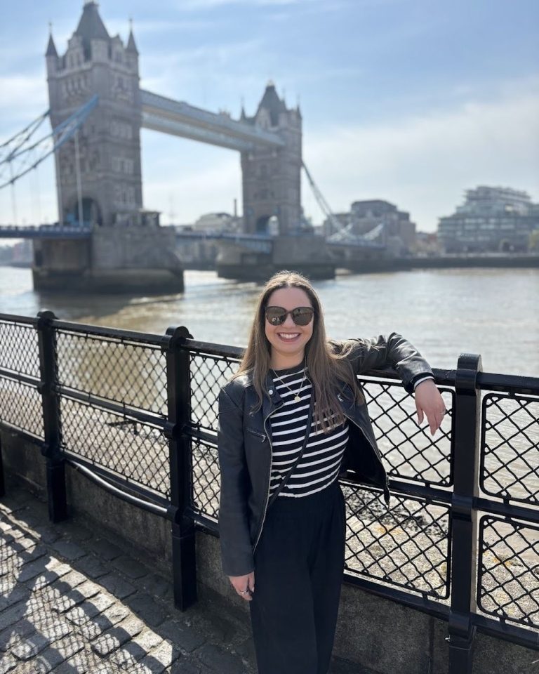 girl posing in front of london bridge from trip planned by travel agent
