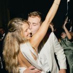 Husband and wife kissing on dance floor during wedding reception