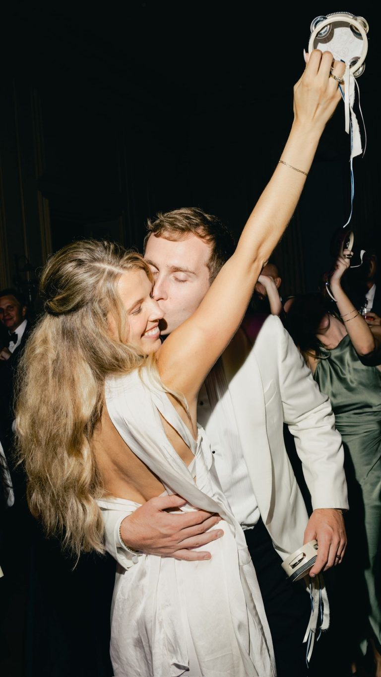 Husband and wife kissing on dance floor during wedding reception