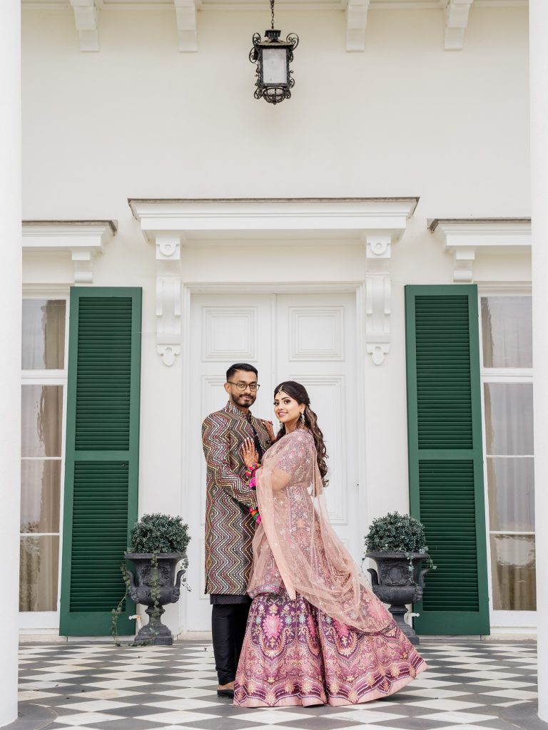 bride and groom posing in front of green shutters at outdoor wedding venue