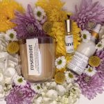 Rosemont candle and apothecary products nestled in a vibrant bouquet of yellow, purple, and white chrysanthemums.