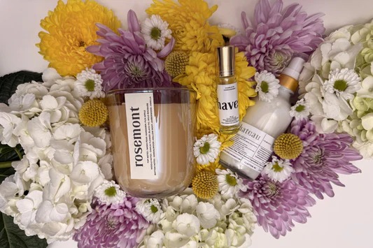 Rosemont candle and apothecary products nestled in a vibrant bouquet of yellow, purple, and white chrysanthemums.