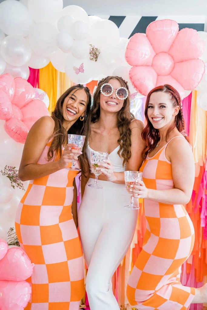 Bubbly bridal party inspiration featuring retro-chic checkered dresses, pearl-rimmed sunglasses, and a playful floral balloon installation.