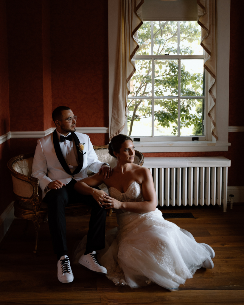 Moody style photo husband and wife sitting in lounge area looking off into the distance