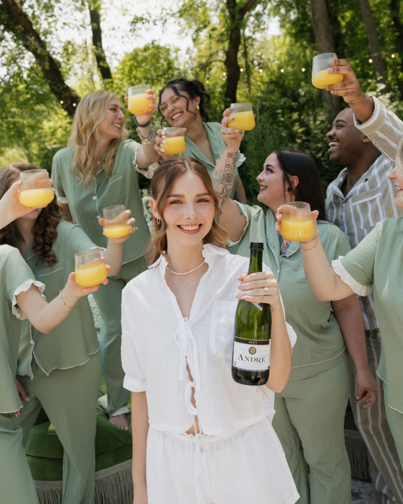 Coordinated bridesmaids pajamas in sage green for a fun, pre-wedding getting ready champagne toast.