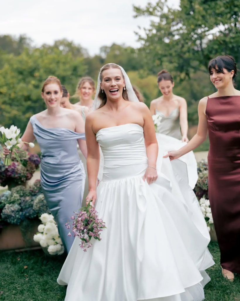 bride and bridesmaids walking towards camera outdoor wedding ceremony venue with mismatched bridesmaid dresses