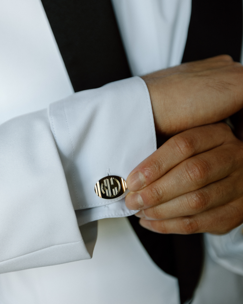 close up of groom putting on cufflink from brides deceased father to pay tribute
