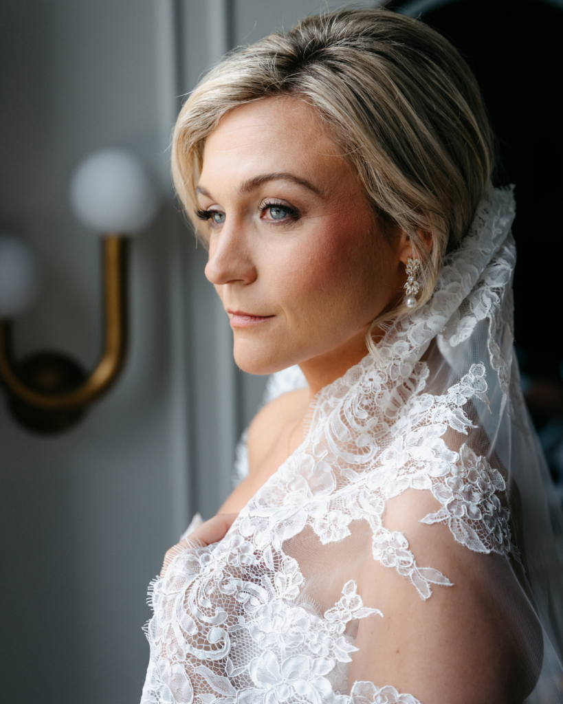 Close up bridal portrait featuring a lace edged veil, pearl earrings, and natural wedding day makeup in Charlotte, North Carolina.