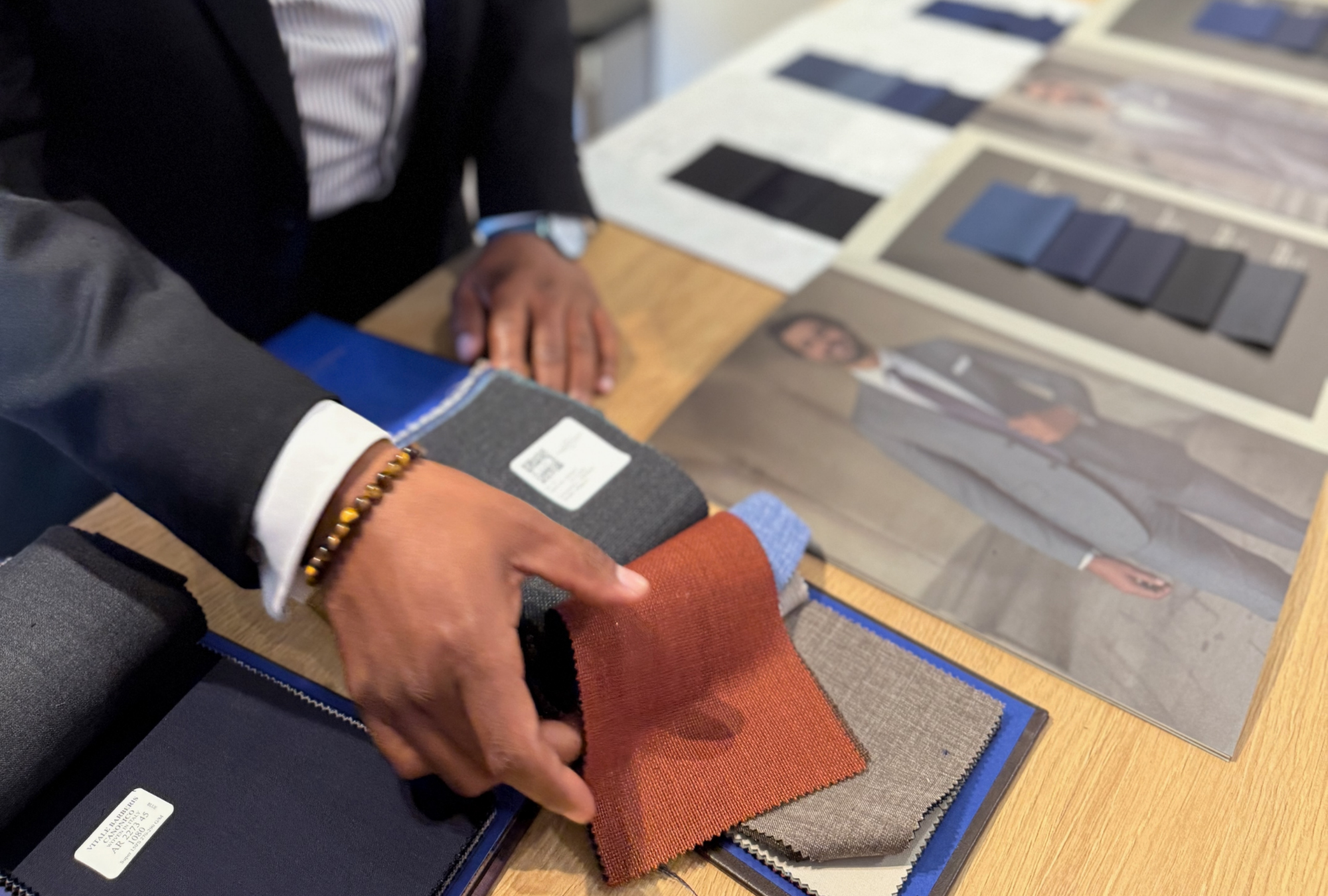 Client reviewing luxury suiting fabrics and swatches during a custom tailoring consultation at Young & Squire in Greenville, Delaware.