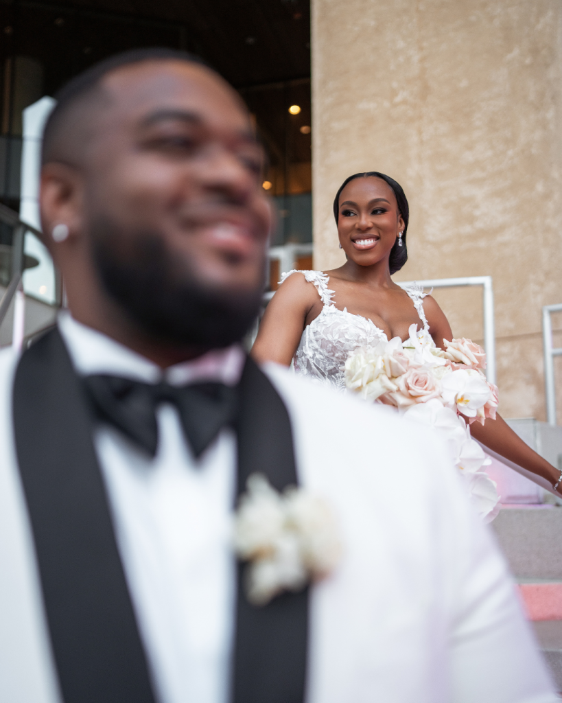 Bride Jessica smiles at groom Triston during wedding portraits outside The Mint Museum in Uptown Charlotte.