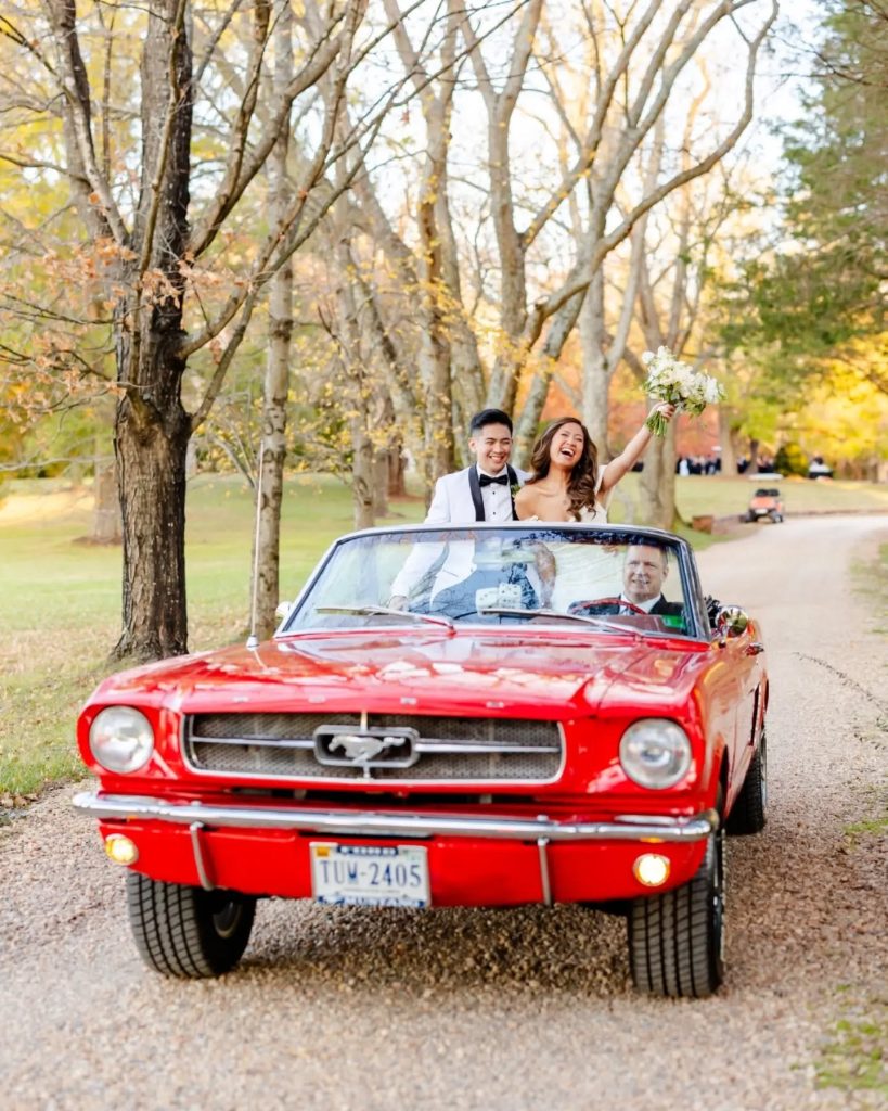 bride and groom cheering together in vintage red car in northern virgina estate