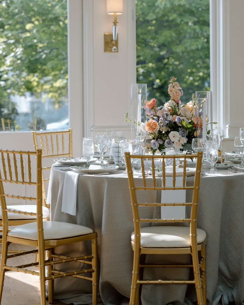 Tablescape reception view with soft pastel colors and large floral centerpieces. table looks out the window