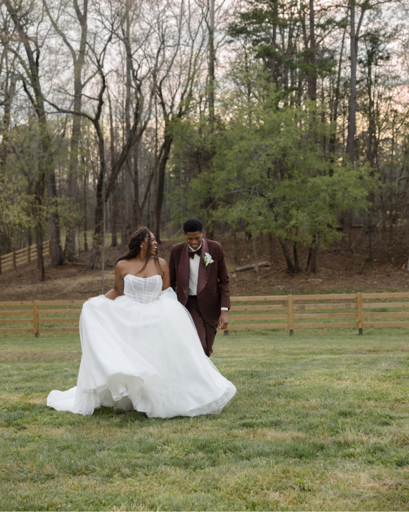 Bride and groom walk together across the lawn at The Lumen House surrounded by natural North Carolina scenery during golden hour portraits.