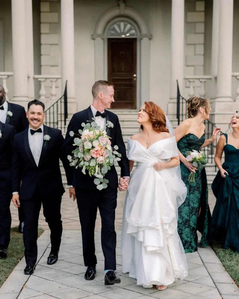 bride and groom looking at each other after wedding ceremony walking towards camera with wedding party in northern virginia