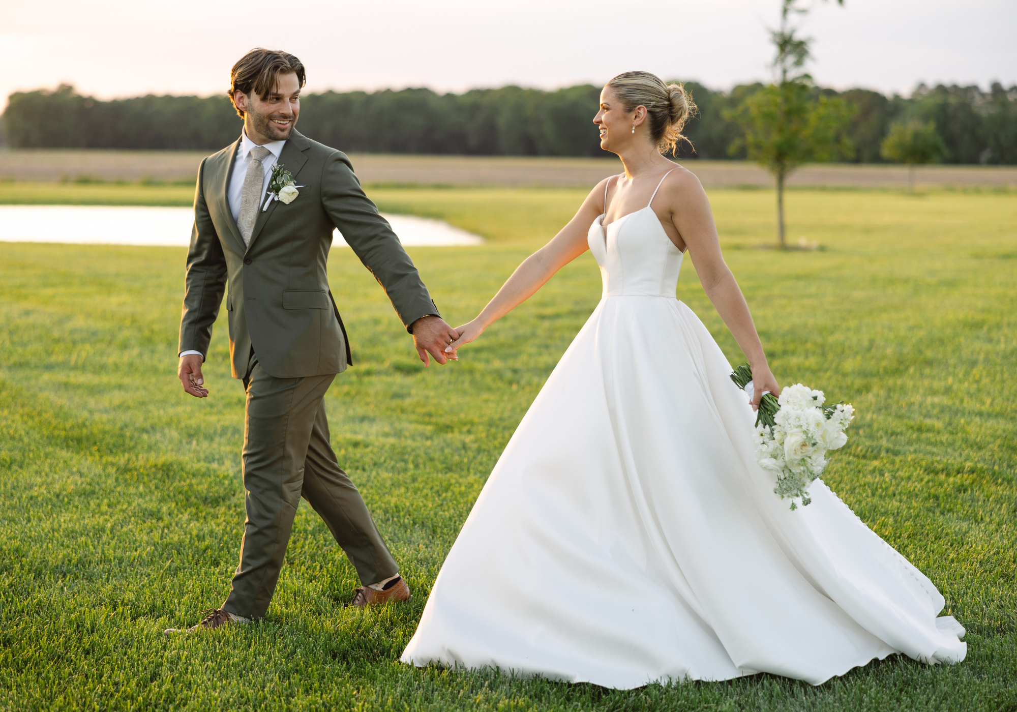 Bride and groom holding hands while walking across the lawn during their elegant Maryland Eastern Shore wedding.