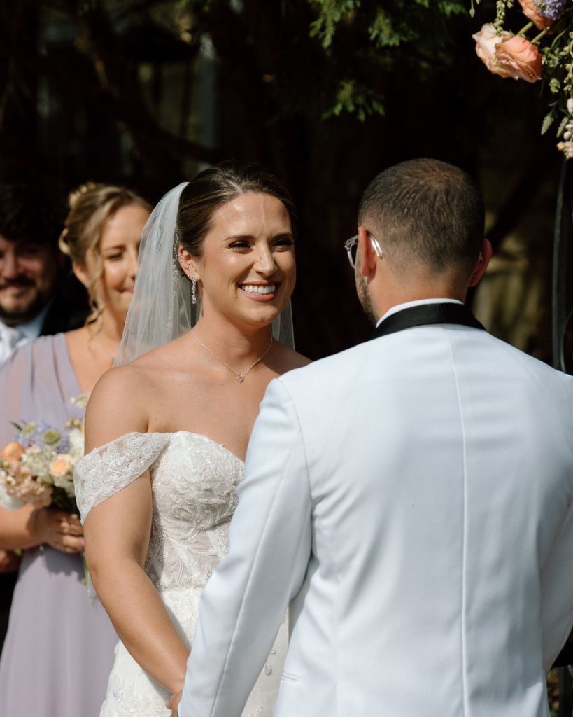 wife smiling at husband at wedding ceremony holding hands at outdoor wedding ceremony northern vriginia
