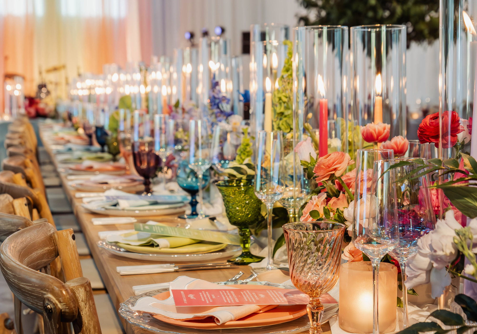 Color-coded wedding reception tablescapes at Kent Island Resort with colorful glassware, taper candles, florals, and layered place settings.