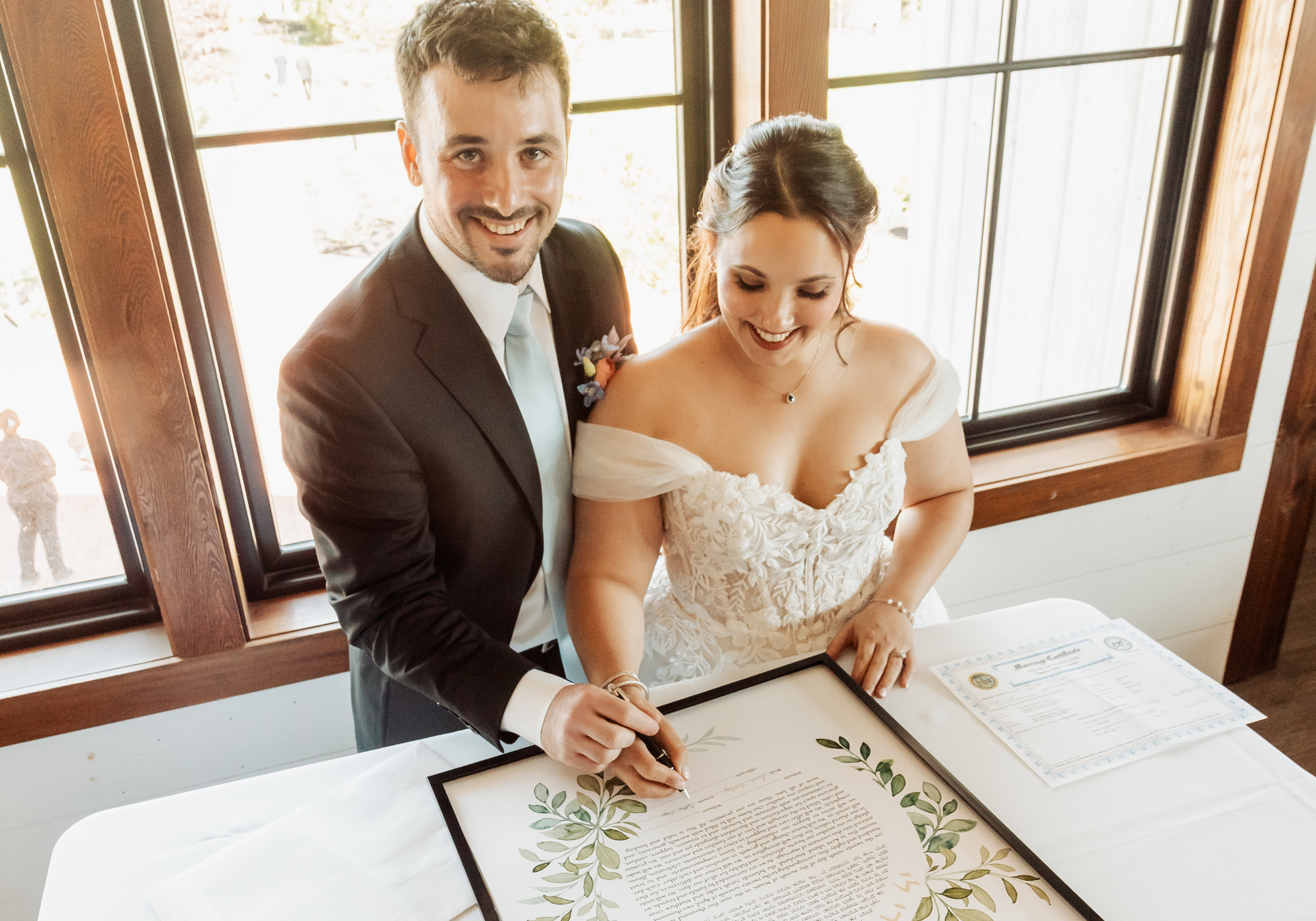 Bride and groom signing their ketubah before their wedding ceremony at Kent Island Resort.