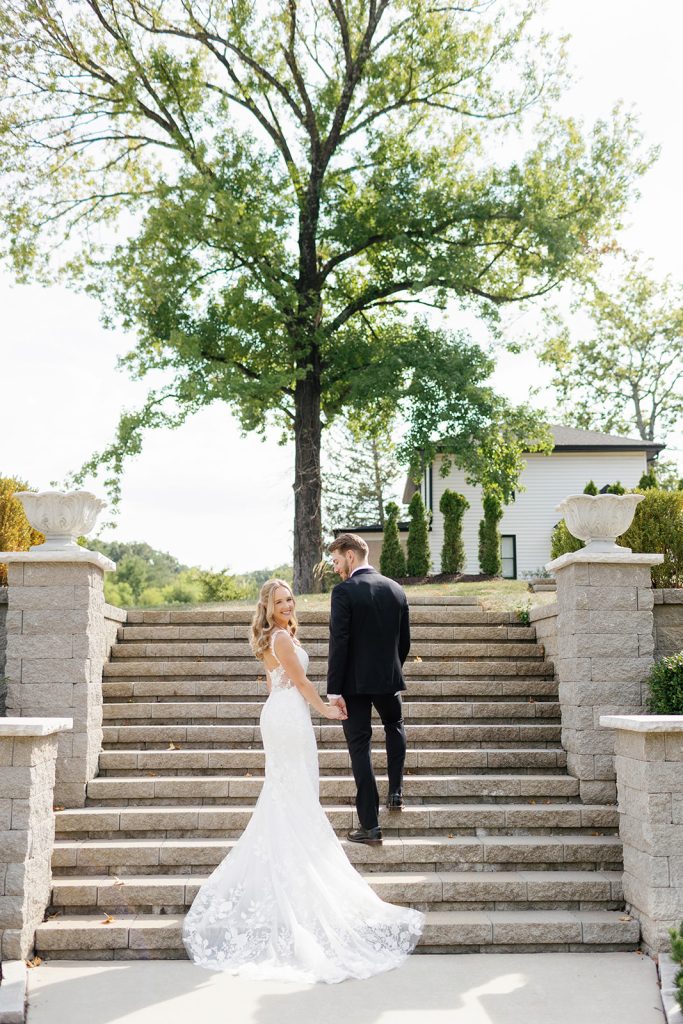 Bride and groom walking up the grand outdoor stairs at Knotting Hills Wedding Venue & Resort.