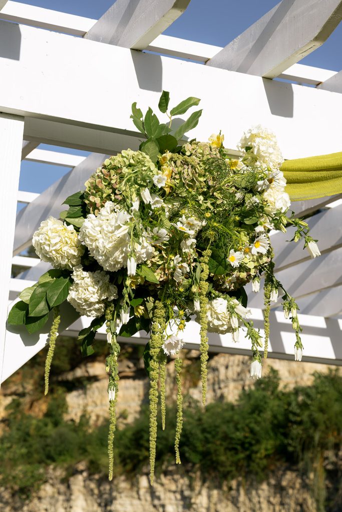 Ceremony arbor accentuated with white and green florals by Cultivated Blooms.