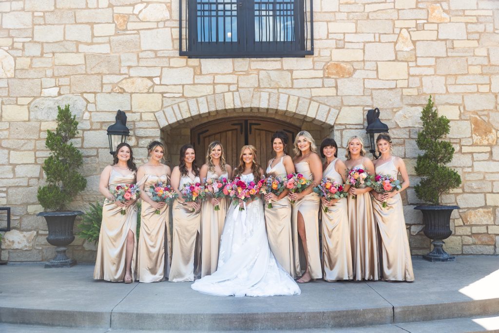 Bride with her bridesmaids in front of stone facade at Silver Oaks Chateau.
