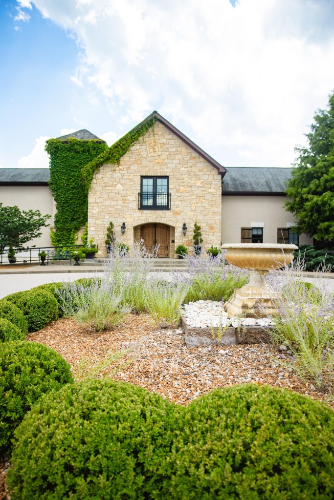Exterior view of the stone facade entrance and manicured courtyard fountain at Silver Oaks Chateau.