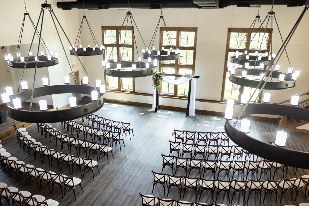 Overhead view of the indoor wedding ceremony space with large iron chandeliers and wooden chairs at Silver Oaks Chateau.