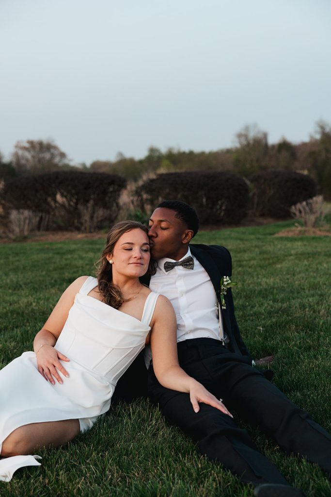 bride and groom in field sitting relaxing after wedding ceremony in northern virginia