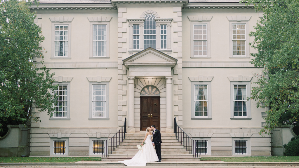 husband and wife kissing infront of wedding venue mansion