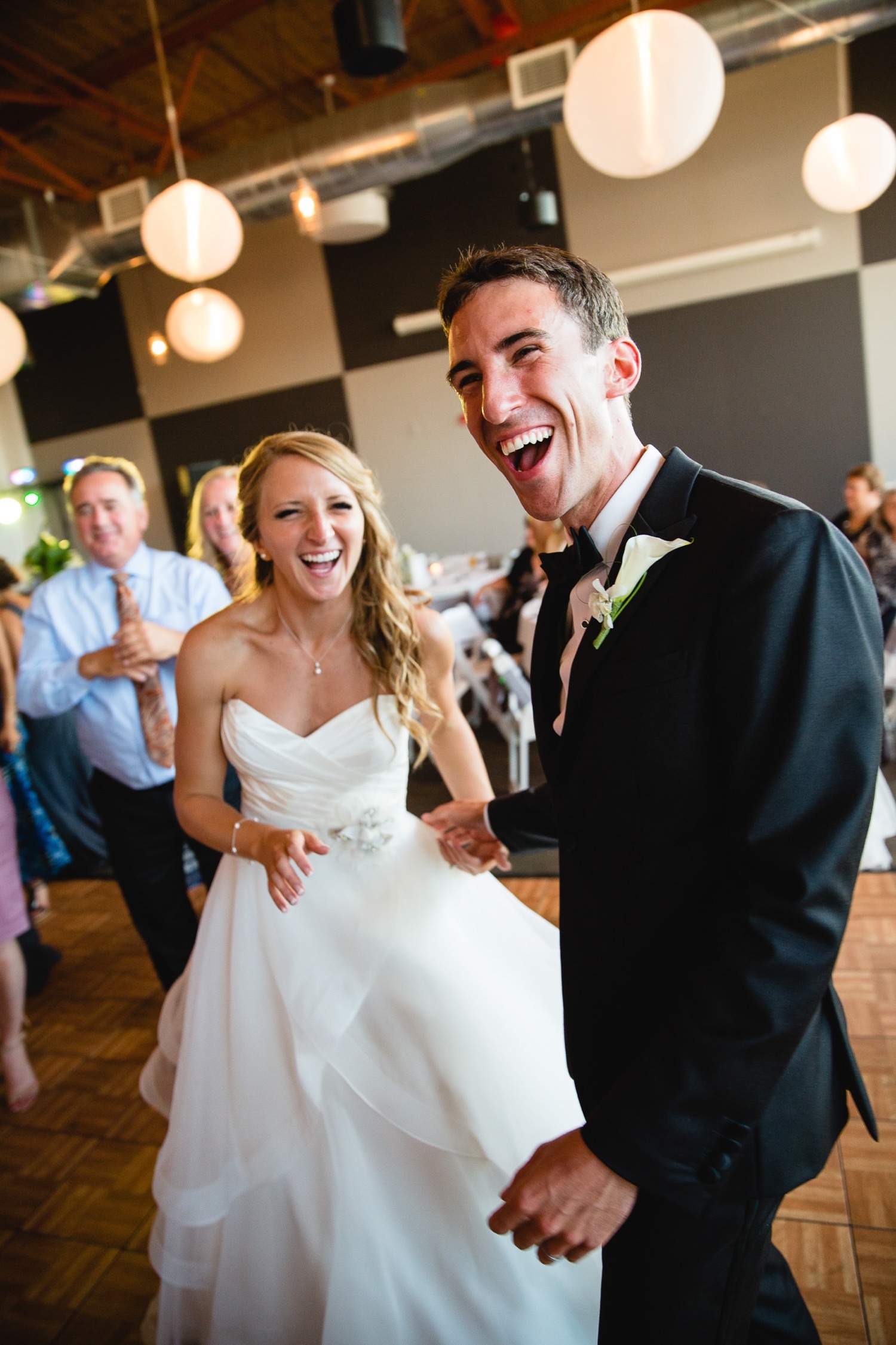 Bride and groom laughing together on the dance floor during their wedding reception.