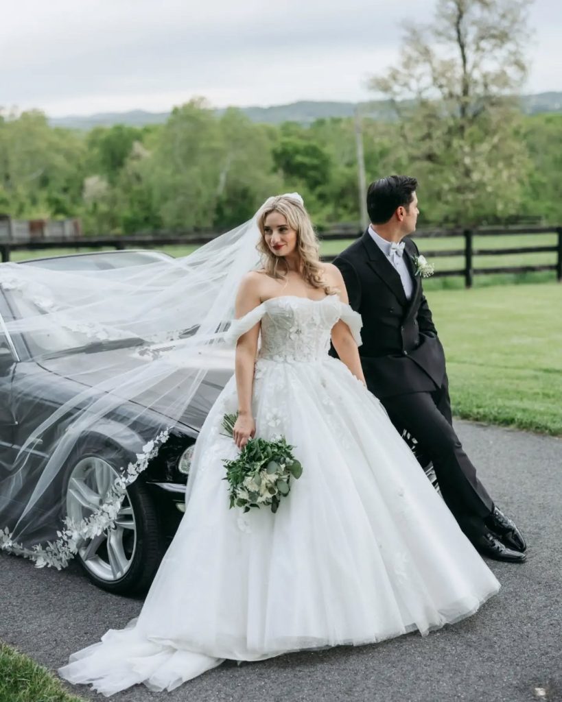 bride and groom looking off into distance while leaning on vintage car outside luxury wedding venue in northern virginia NOVA