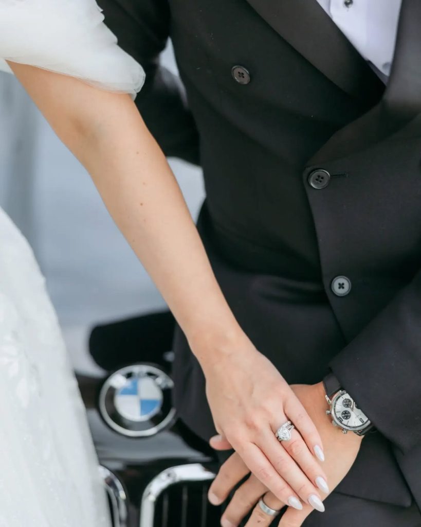 bride and groom holding hands with close up of wedding ring and BMW vintage car