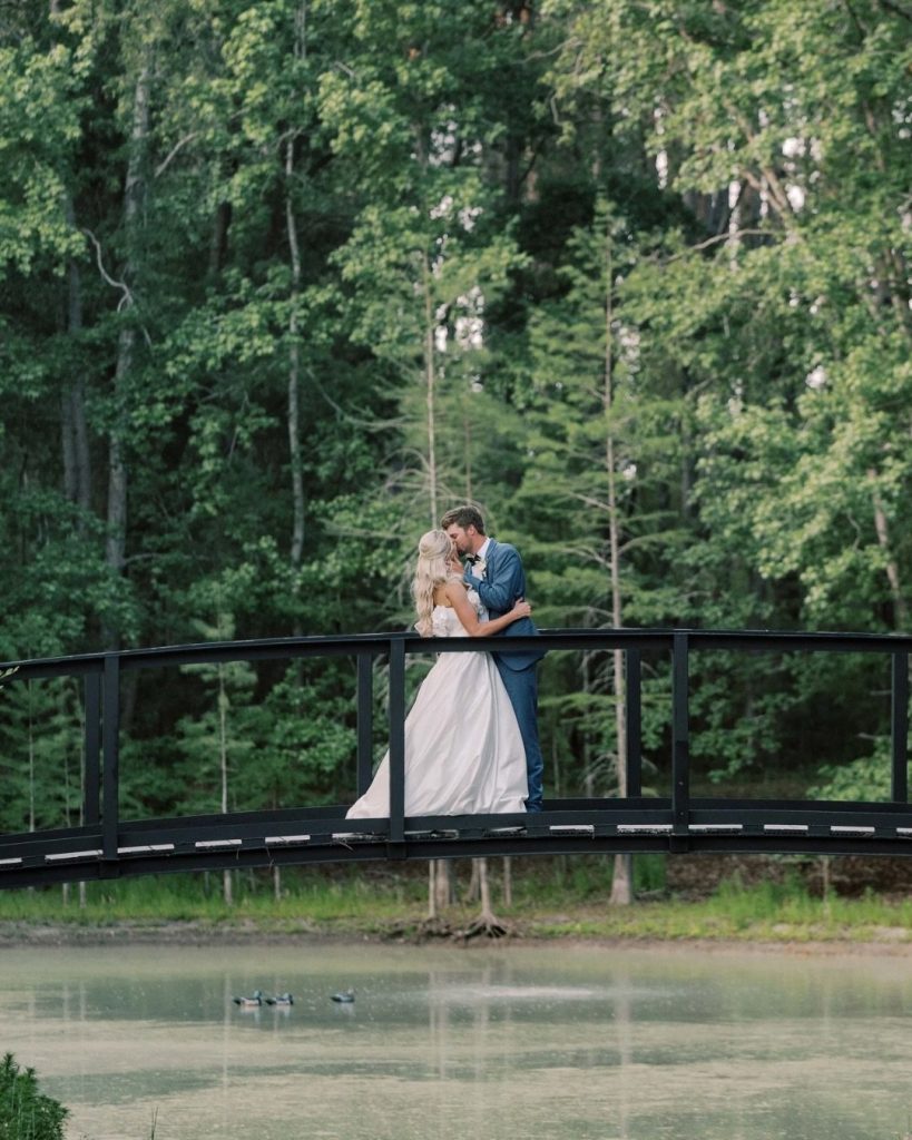 Bride and groom kiss on a bridge over a pond at Chande Pines, photographed by Barefoot Royalty Photography.