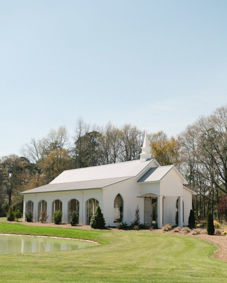 Southern wedding chapel venue exterior featuring modern arched glass windows and a scenic pond layout.