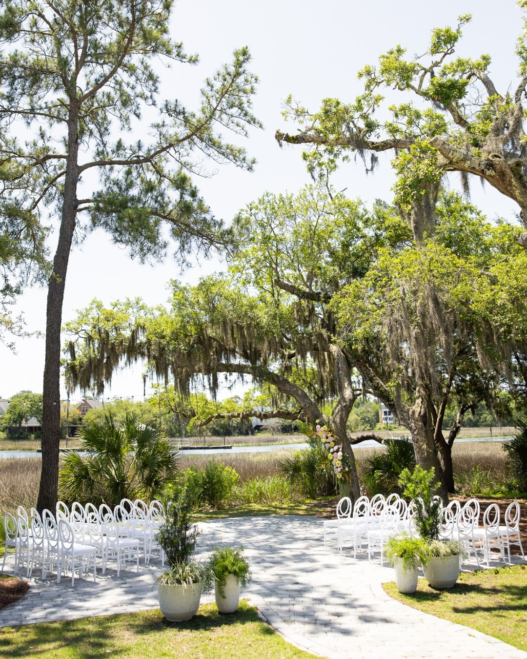 Outdoor wedding inspiration featuring a waterfront ceremony site, modern white chairs, and garden chic floral details.