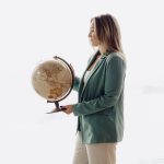Travel advisor holding a vintage globe in a bright studio setting, symbolizing global travel planning and destination expertise.