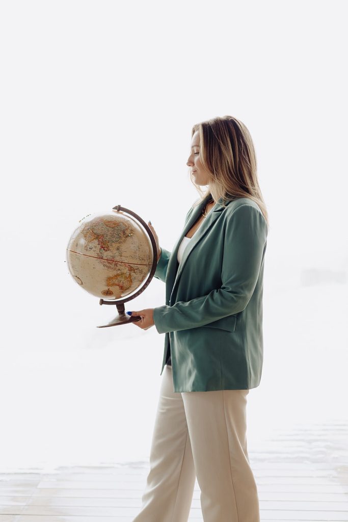 Travel advisor holding a vintage globe in a bright studio setting, symbolizing global travel planning and destination expertise.