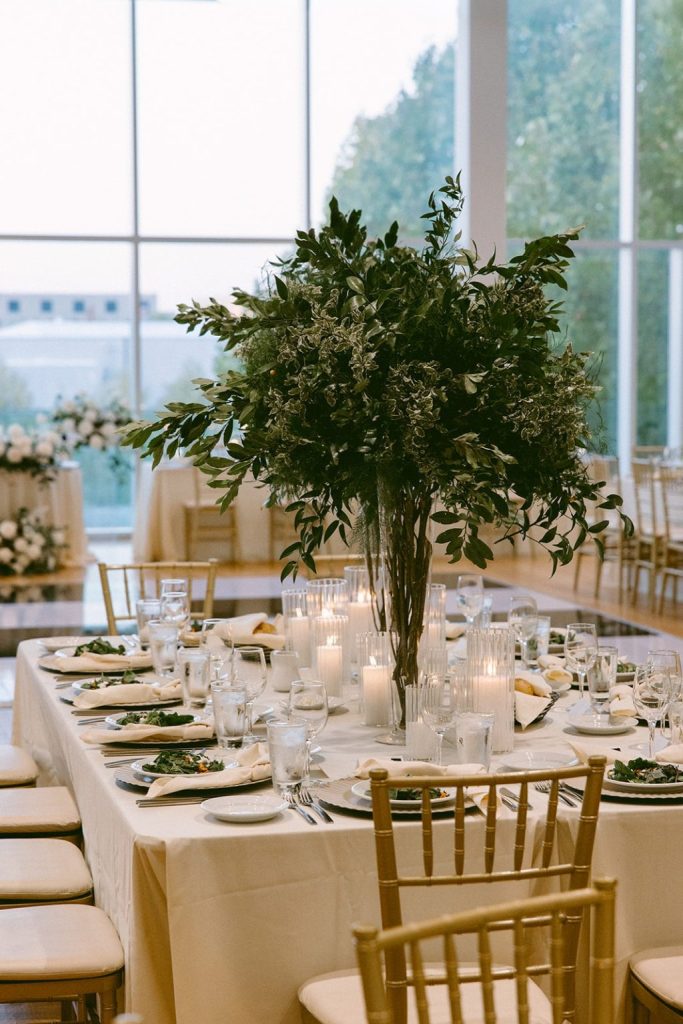Wedding reception table with lush greenery centerpiece, candlelight, and elegant place settings inside a modern Columbus wedding venue.