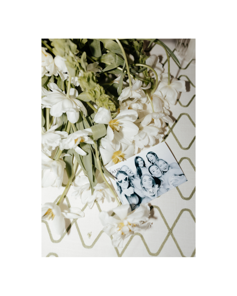 Vintage style photo booth strip resting among white tulips from the couple's reception, highlighting Poza Photo Booth Co.
