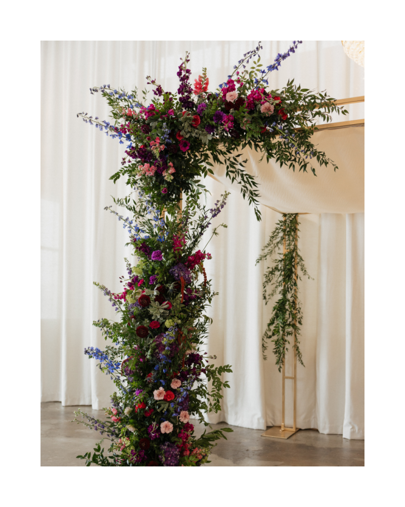 Close view of one side of the floral chuppah featuring lush greenery and jewel toned flowers at The Casey wedding in Charlotte.