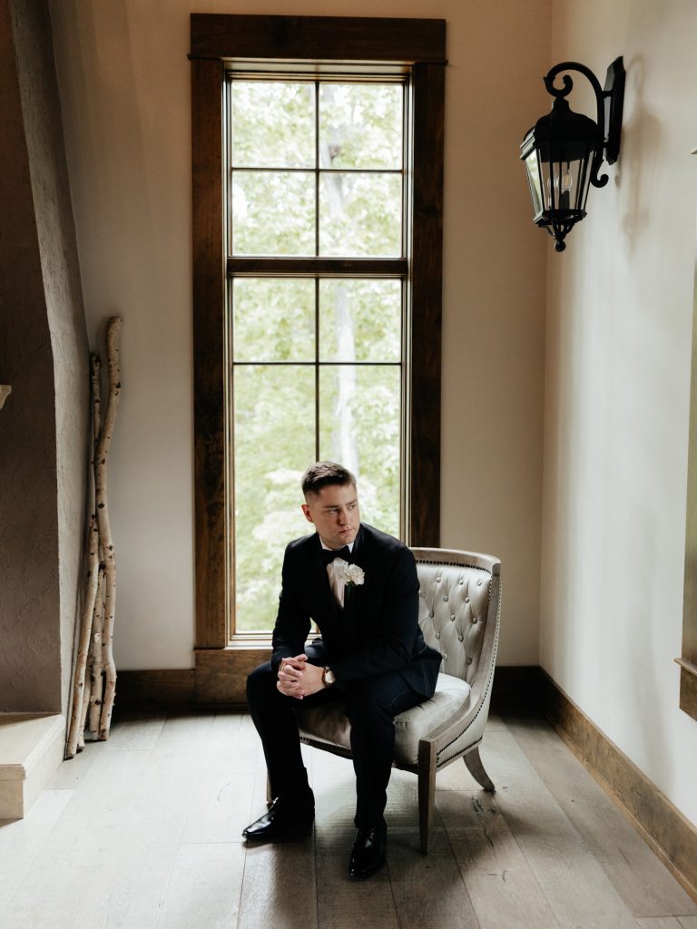 Groom sitting near the fireplace in the groom's suite at Silver Oaks Chateau.