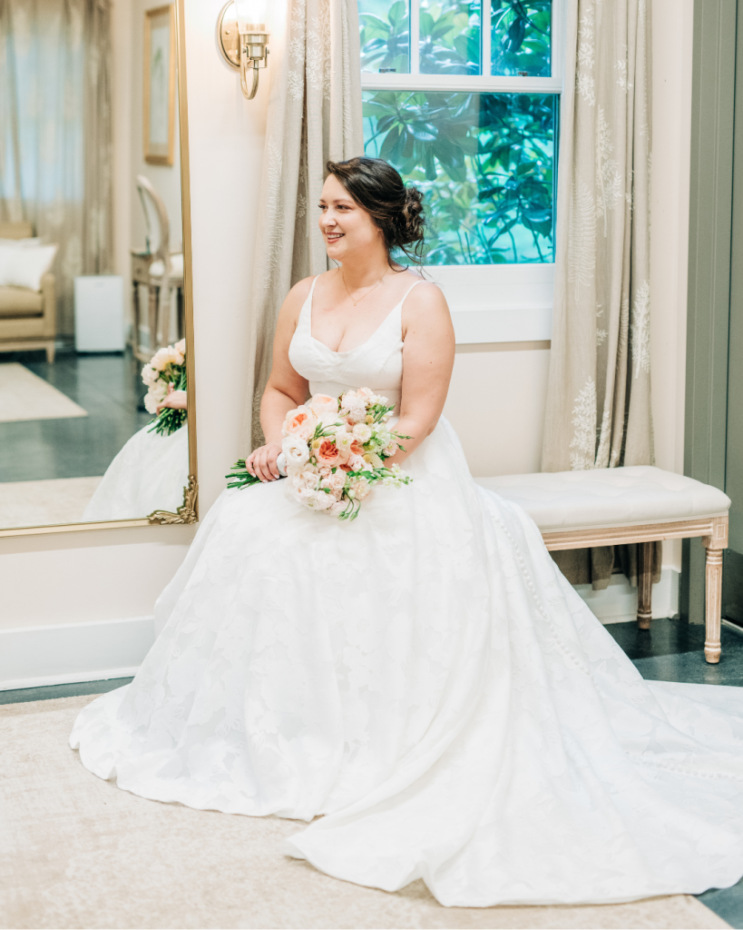 Bride sits by a window holding her bouquet before the ceremony at Daniel Stowe Botanical Garden in Belmont, North Carolina. Soft bridal portrait featured on Wed Society Charlotte.