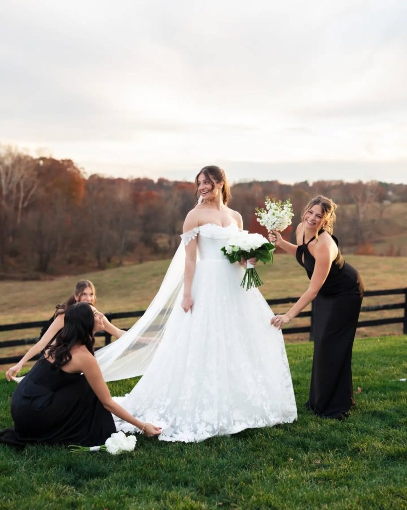 bridesmaids fluffing up brides wedding dress outside at luxury wedding venue during wedding portraits