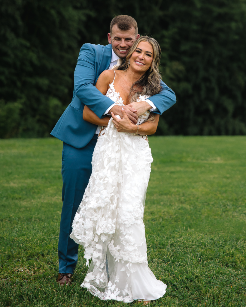 Groom smiles during an outdoor bamboo forest ceremony at Camelot Meadows in Charlotte with lush floral arrangements surrounding the ceremony space.