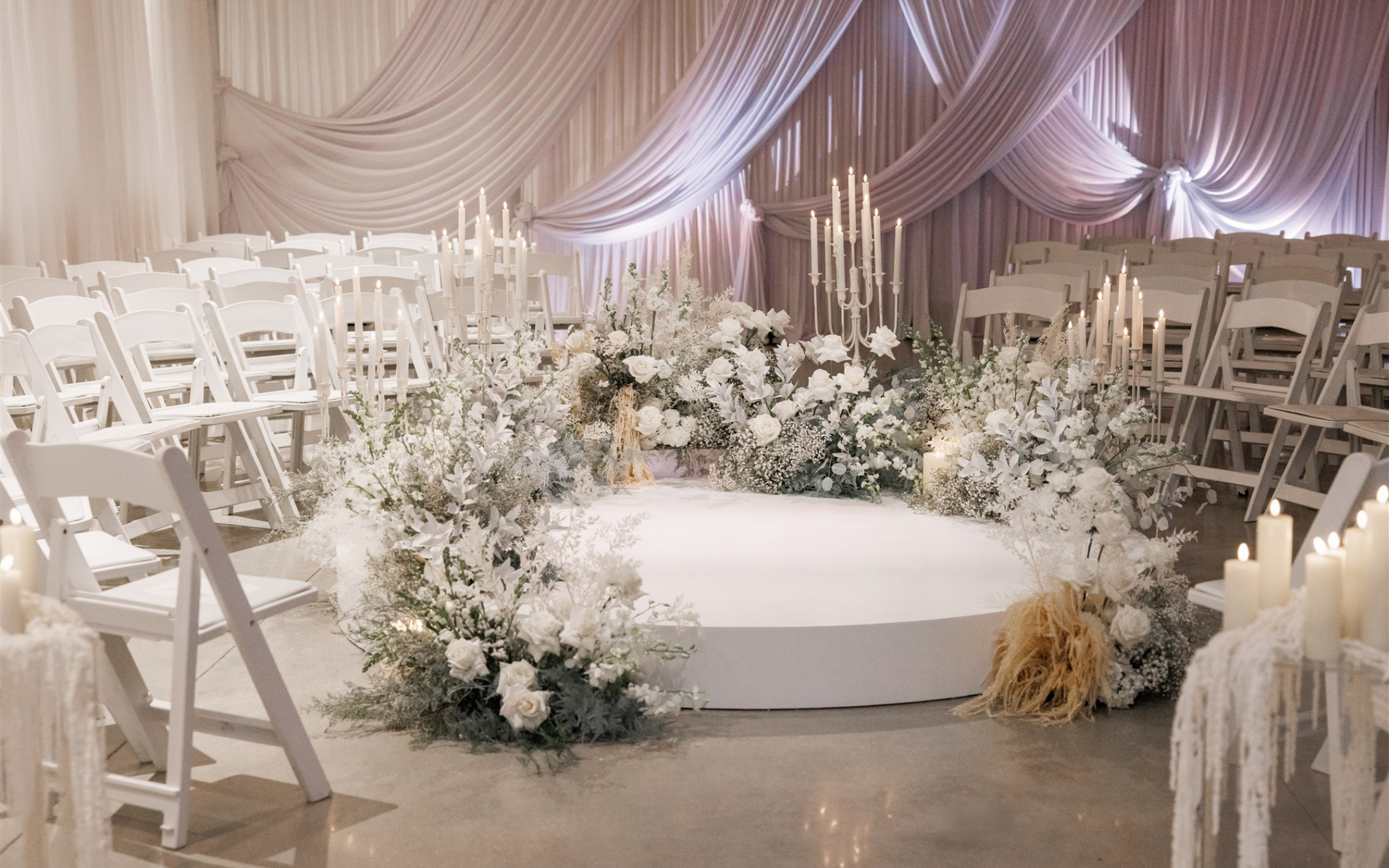 Circular ceremony space at Winterthur surrounded by white florals, candlelight, towering candelabras, and soft draping for an immersive winter wedding ceremony.