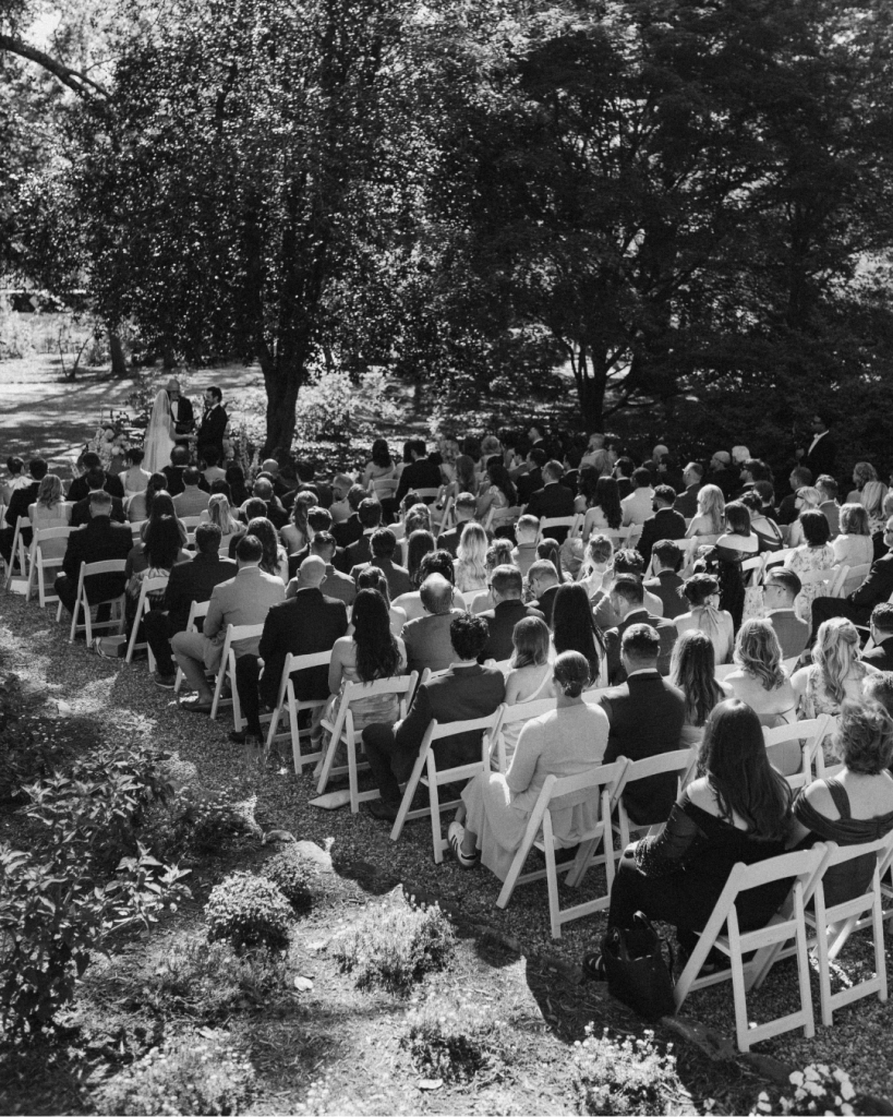 Outdoor ceremony at The VanLandingham Estate with guests seated beneath mature trees during a spring wedding.